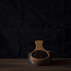 Dark roasted coffee beans in a wooden scoop against a dark backdrop, representing Boa Vista Natural