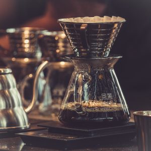 Warm pour-over coffee brewing scene with glass carafes and a gooseneck kettle, representing El Cielo Antigua