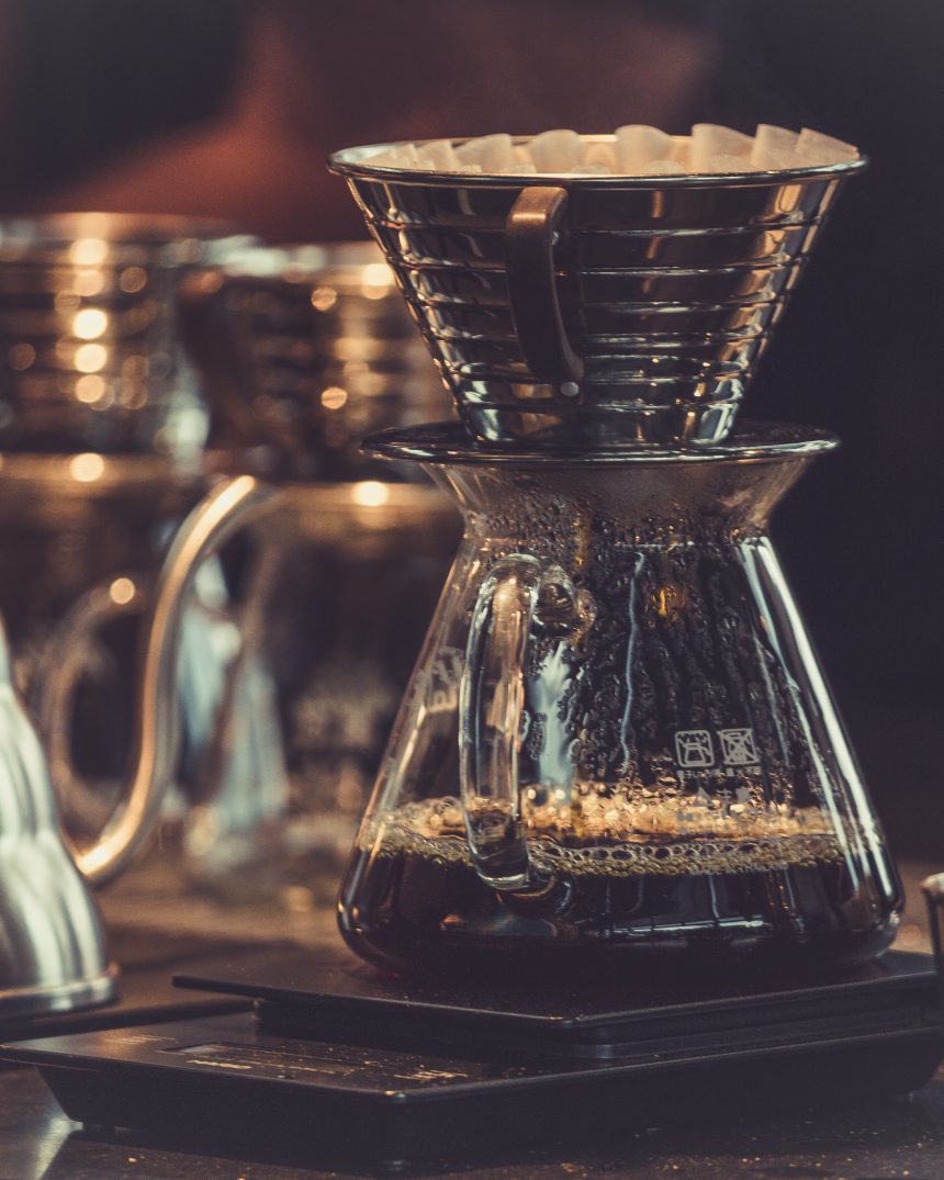 Warm pour-over coffee brewing scene with glass carafes and a gooseneck kettle, representing El Cielo Antigua