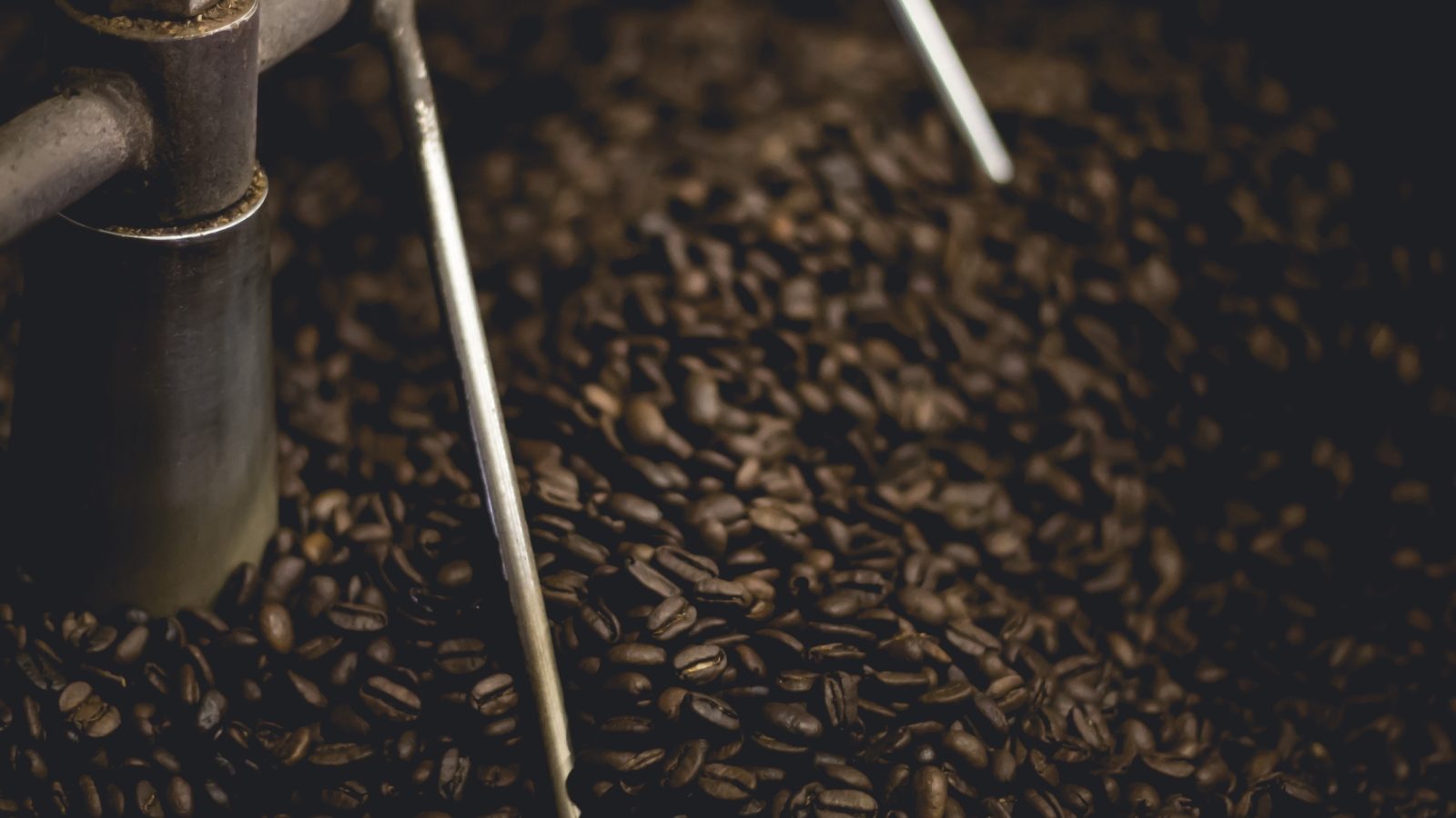 Dark roasted coffee beans in a roasting drum, representing Gunung Kerinci Wet-Hulled
