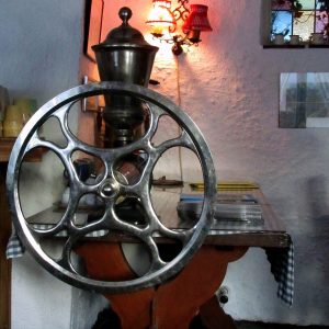 Large table-mounted manual coffee mill with a big spoked wheel