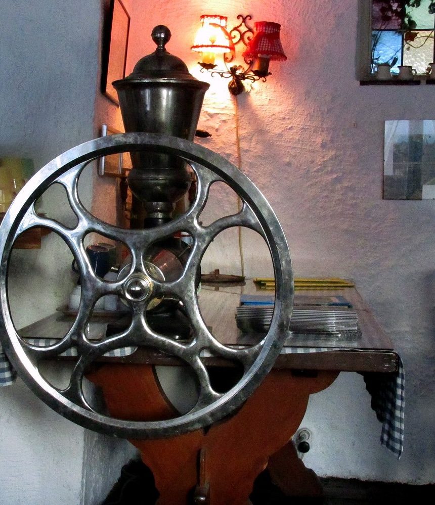 Large table-mounted manual coffee mill with a big spoked wheel