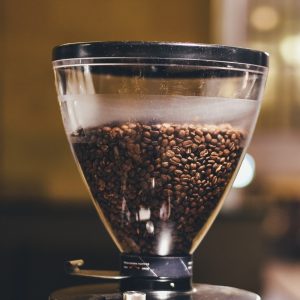 Two commercial electric coffee grinders with full bean hoppers side by side