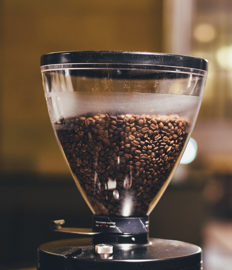 Two commercial electric coffee grinders with full bean hoppers side by side