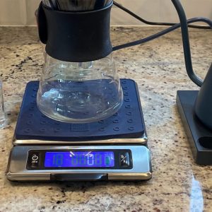 Gooseneck kettle beside a pour-over dripper and carafe resting on a digital coffee scale